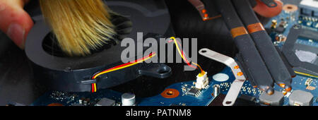 Notebook cooling system cleaning with a brush during service maintenance. Stock Photo