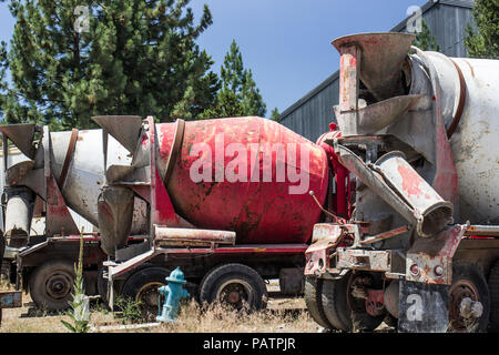 Row Of Abandoned Cement Mixer Trucks In Salvage Yard Stock Photo