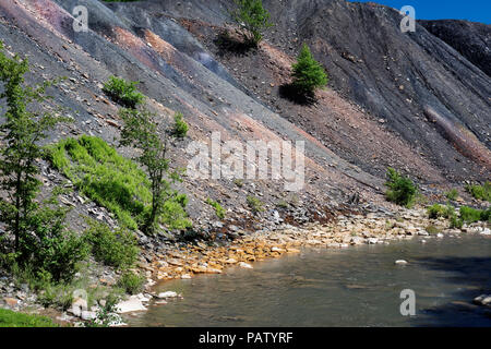 Coal mine tailings waste spoil pile beside a stream with orange rocks ...