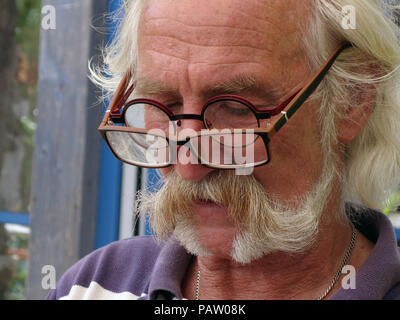 Silver haired man wearing two pairs of glasses at the same time Stock Photo