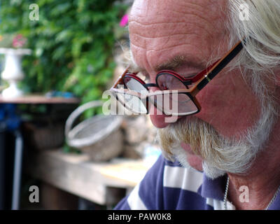 Silver haired man wearing two pairs of glasses at the same time. Property and Model released Stock Photo