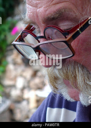 Silver haired man wearing two pairs of glasses at the same time. Property and Model released Stock Photo