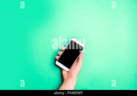 smartphone, phone in male hands on a green background. the concept of communication. use of gadgets, modern technologies. social networks. place for t Stock Photo