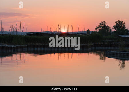 The summer sun setting over yacht masts at Neusiedler See, a large inland lake and popular tourist destination in Burgenland, Austria Stock Photo