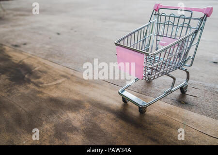 Small shopping cart,Empty shopping trolley on wooden floor. Stock Photo