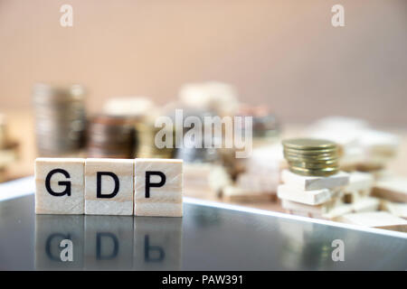 GDP  Word Written In Wooden Cube reflection on black mirrow with money stack as graph in background Stock Photo