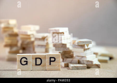 GDP Word Written In Wooden Cube on wood table with wooden stack as graphs in background Stock Photo