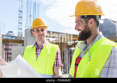 Two young construction workers analyzing together a plan Stock Photo