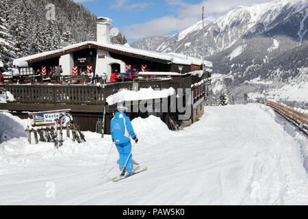 BAD HOFGASTEIN, AUSTRIA - MARCH 9, 2016: People ski by apres ski restaurant in Bad Hofgastein. It is part of Ski Amade, one of largest ski regions in  Stock Photo