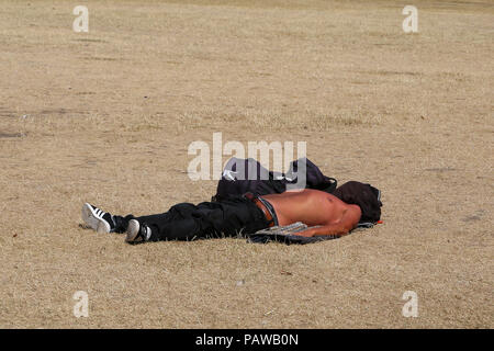Hyde Park. London. UK 25 July 2018 - A man sunbathes on the parched grass Hyde Park on a very hot and humid day in the capital. According to the Met Office the temperature in London and South East is likely to reach 35 degree celsius on Thursday.    Credit: Dinendra Haria/Alamy Live News Stock Photo