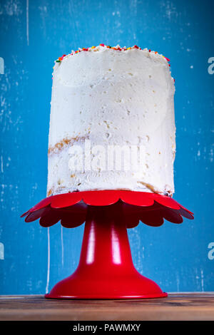 Simply Frosted Cake and Stand in front of blue background Stock Photo