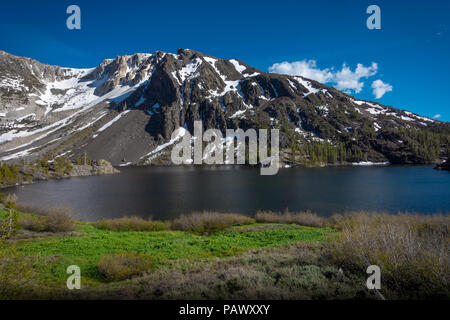 Beautiful Ellery Lake and mountain, with melting snow patches in spring sunshine - Tioga Pass, Yosemite National Park Stock Photo