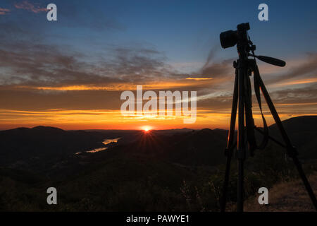 Landscape photography gear, including tripod and dslr camera - looking out over a stunning mountain lake and sunset - Priest Grade Road, near Yosemite Stock Photo
