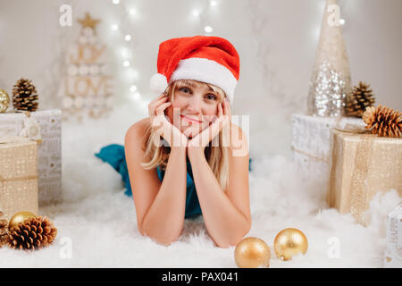 Portrait of blonde Caucasian young woman with brown eyes in santa claus hat celebrating Christmas or New Year holiday Stock Photo