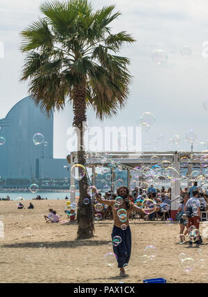 Barcelona, Spain - May 8, 2018: Man making a lot of soap bubbles on Barceloneta beach in sunny day. Barceloneta beach in colorful soap bubbles. Stock Photo