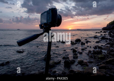 A mirrorless camera and lens on tripod - taking long exposure sunset photos on a beautiful, rocky island beach -Malapascua Cebu - Philippines Stock Photo