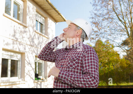 mature building engineer on the phone at construction site Stock Photo