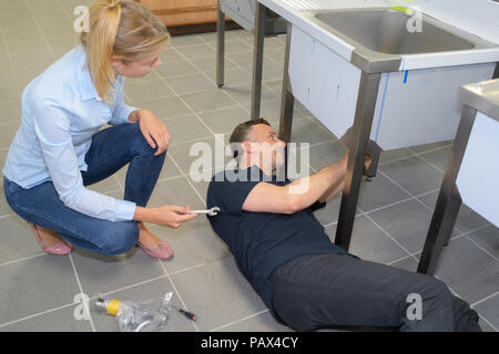 male plumber in overall fixing sink pipe Stock Photo