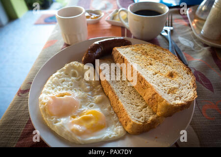 Fresh resort breakfast of coffee, fried eggs sausage, and homemade bread on plate - Port Barton, Palawan - Philippines Stock Photo