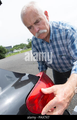 old man installs tail light on the vehicle Stock Photo