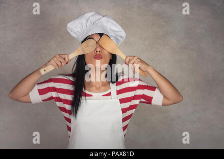 funny woman with wooden spoons in his eyes on gray background Stock Photo