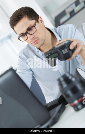 young technician working on broken camera in his office Stock Photo