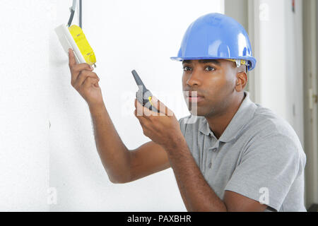 electrician installs paired socket on the wall Stock Photo