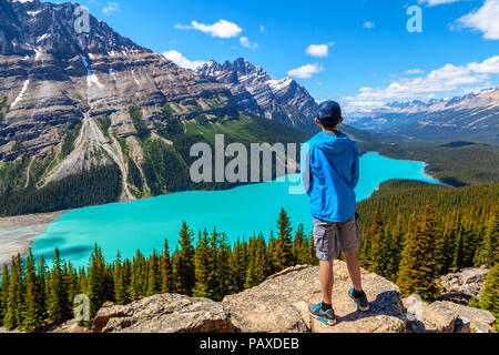 A teen hiker looks at Peyto Lake from Bow Summit in Banff National Park on the Icefields Parkway. The glacier-fed lake is famous for its unique color Stock Photo