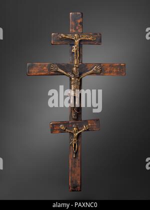 Triple Crucifix. Culture: Kongo peoples; Kongo Kingdom. Dimensions: H. 10 1/4 in. (26 cm), W. 5 3/4 in. (14.5 cm), D. 1 in. (2.5 cm). Date: Central figure,16th-17th century; top and bottom figures, 18th-19th century.  This composite artifact may be an interpretation of the Trinity. The three individually cast Christ figures were affixed to the wood cross with nails and copper loops. The central one is more finely rendered and may be earlier in date. Among the varieties of European crosses in eighteenth-century Kongo that may have served as a point of reference was the Caravaca form, brought to Stock Photo