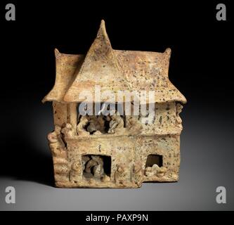 House Model. Culture: Nayarit. Dimensions: H. 12 × W. 10 × D. 6 3/4 in. (30.5 × 25.4 × 17.1 cm). Date: 100 B.C.-A.D. 200.  This model of a two-story Nayarit house depicts a large and complex feasting scene. It shows twenty-six figures engaged in a feast, complete with miniature representations of food and drink, and three birds. The house has two intersecting peaked roofs sheltering both a portico and an enclosed room. Remnants of a diamond pattern painted in black and white on a red slip are visible on the tops of the roofs, representing thatched roofs that would have been plastered and paint Stock Photo