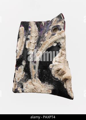 Glass cameo panel fragment. Culture: Roman. Dimensions: Overall: 3 3/4 x 2 5/8 in. (9.5 x 6.7 cm). Date: ca. A.D. 1-25.  Translucent deep purple, appearing black with opaque white overlay.  Thick, flat panel.  Decoration in deep relief, comprising a floral scroll with tendrils and leaves.  Broken on all sides with weathered edges; one large weathered bubble on surface; pitting, dulling, thick creamy weathering, and iridescence.  This is part of a large revetment panel decorated with acanthus scrolls, similar to another fragment (18.145.38a) on display in the Augustan Gallery (Gallery 166). Ind Stock Photo
