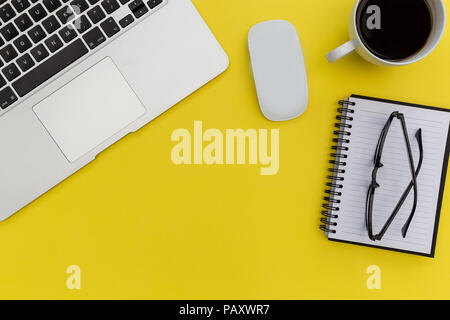 Laptop computer mouse and notebook on bright yellow background Stock Photo