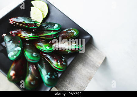 Tasty mussels on black square plate in white background. Stock Photo