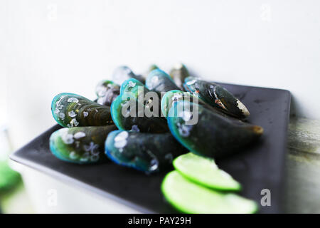 Tasty mussels and sliced lime on dark square platein white background. Stock Photo