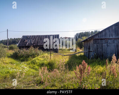 Rural wooden sheds for storing inventory in a blooming summer field on a sunny warm day Stock Photo