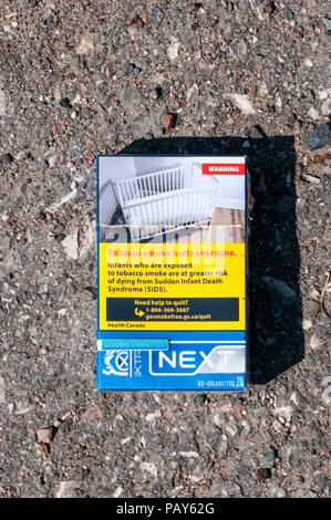 Health warning on a discarded packet of Canadian cigarettes links smoking to Sudden infant Death Syndrome. Stock Photo