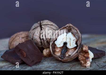Close-up of whole and split walnuts with chunks of dark chocolate on a cutting board Stock Photo
