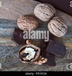 Close-up of whole and split walnuts with chunks of dark chocolate on a cutting board Stock Photo