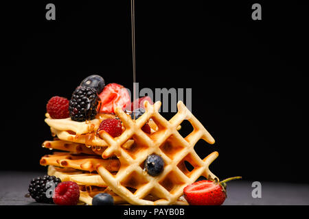 Photo of viennese wafers with berries pouring honey on black empty background Stock Photo