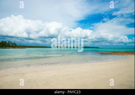 View of a remote Brazilian beach with calm lagoon water and shadows of palm trees falling on the shore in Bahia, Brazil Stock Photo
