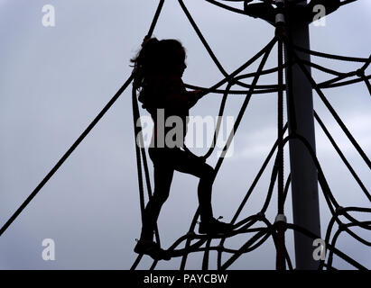 A silhouette of a young girl (6 yr old) on a rope climbing frame Stock Photo
