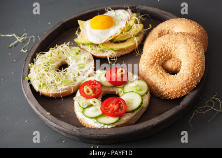 variety of sandwiches on bagels: egg, avocado, tomato, soft cheese, alfalfa sprouts Stock Photo