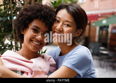 Two smiling friends looking at a camera, standing outdoors Stock Photo