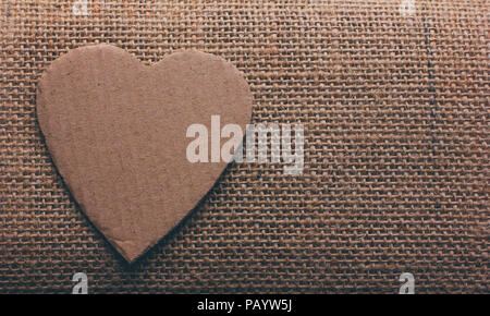 the heart symbol cut out from cardboard on burlap closeup with space for your text Stock Photo