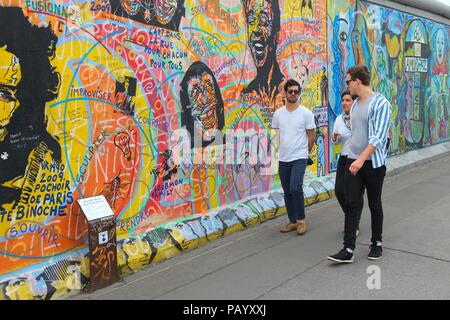 BERLIN, GERMANY - AUGUST 26, 2014: Tourists visit free public urban art of East Side Gallery at public street in Berlin. Part of former Berlin Wall is