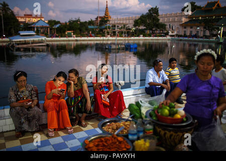 A group of people enjoys sunset in a park near Mahamuni Pagoda in Mandalay, Myanmar. Stock Photo