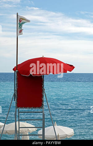 Red  lifeguard tower with white flag over clear blue sky Stock Photo