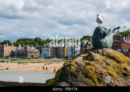 Herring gull Larus argentatus on Sandy Seal statue with Milsey Bay, seaside houses and outdoor bathing pool, North Berwick, East Lothian, Scotland, UK Stock Photo
