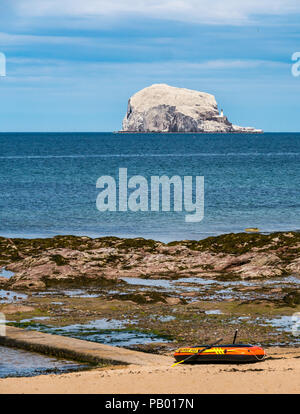 Inflatable rowing boat on beach with Bass Rock and lighthouse on horizon white with nesting gannets, Milsey Bay, North Berwick, East Lothian, Scotland, UK Stock Photo