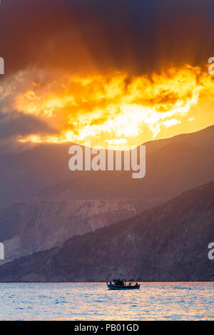 Shoots of light from the sky trough the mountain slopes to the sea Stock Photo